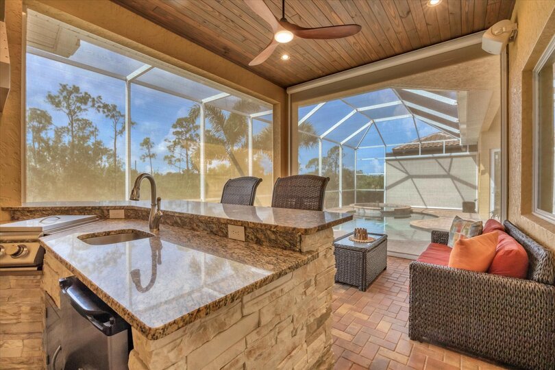 Large outdoor living space overlooking canal and nature preserve. Lanai features ample seating, outdoor kitchen, bar, 65-inch Smart TV, sparkling private pool & spa, and remote controlled privacy screens