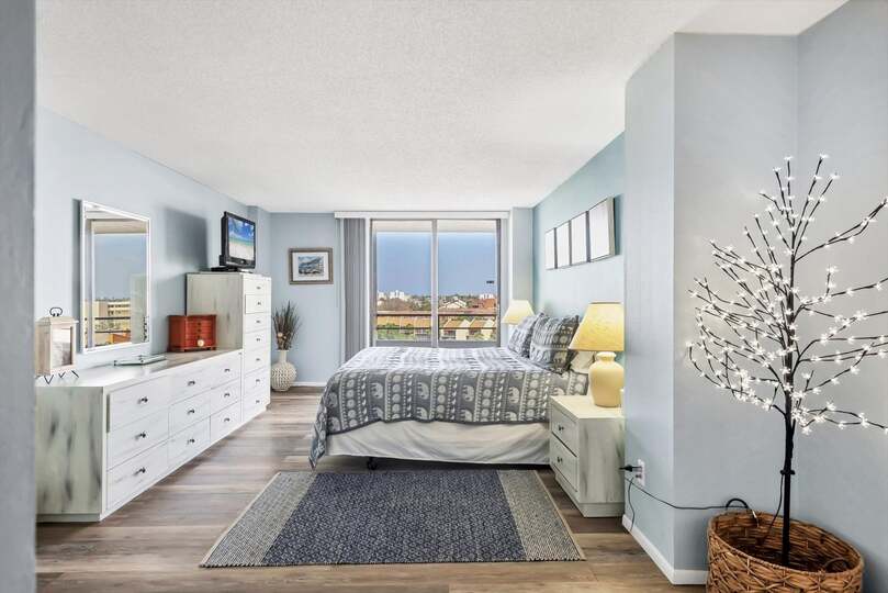 Primary Bedroom with king bed, en suite, balcony access, and a 32" TV