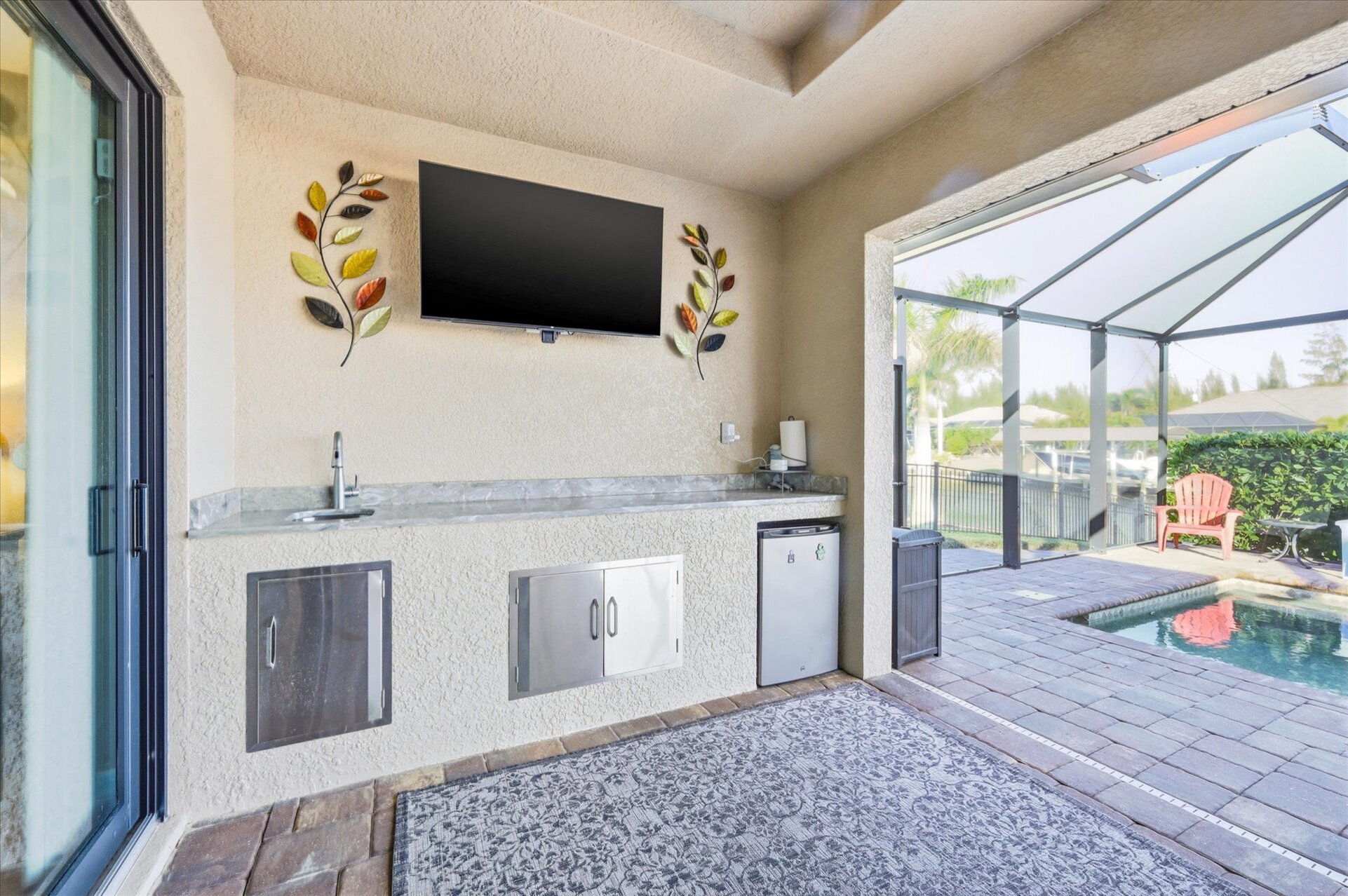 Large outdoor living area overlooking the sparkling pool and canal. Great for entertaining. Features a dining table that seats 6, BBQ grill, outdoor kitchen, Conversation furnite set, and 43" Smart TV