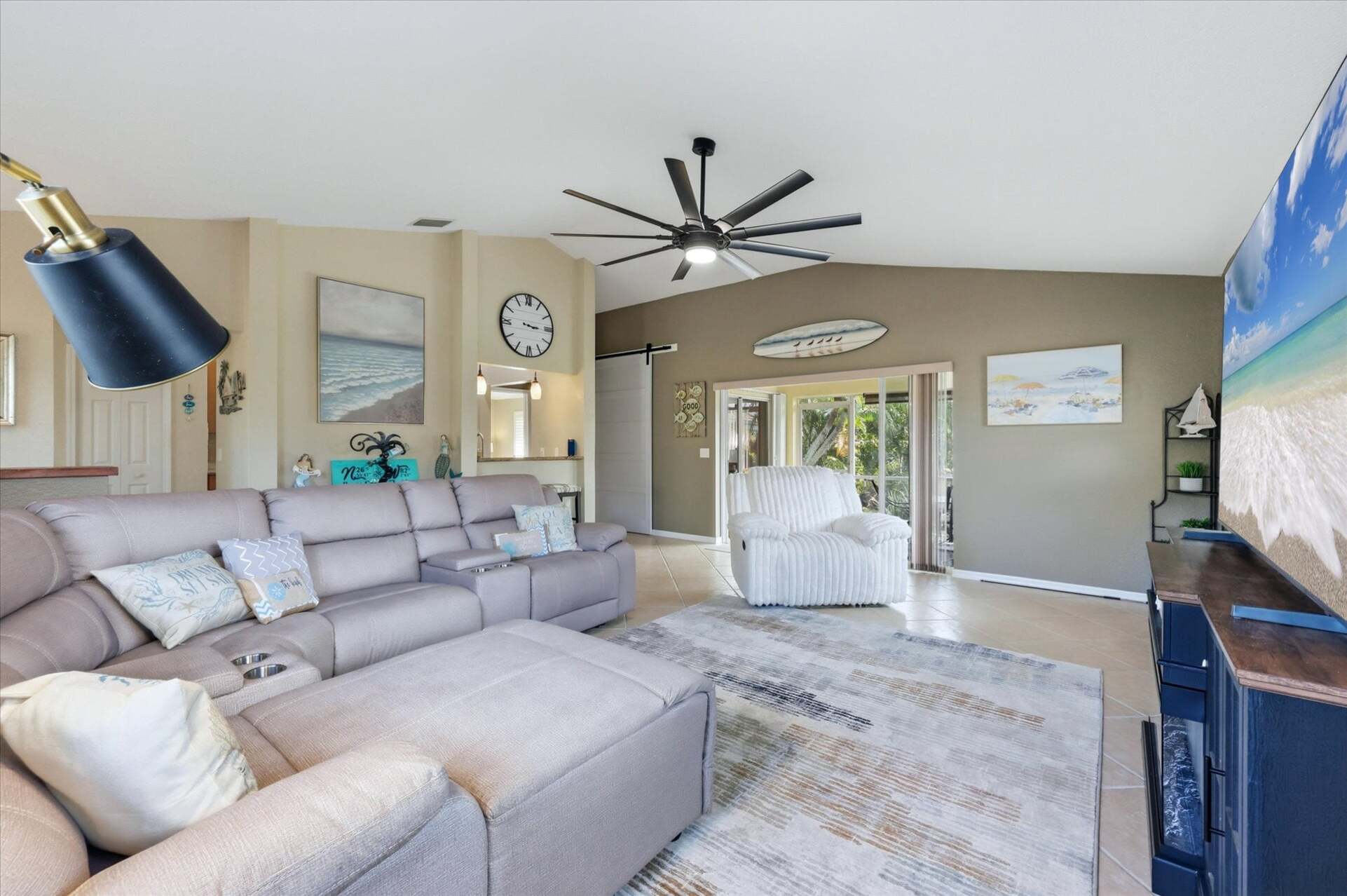 Living room features lots of comfy seating, patio access, and 85-inch Smart TV