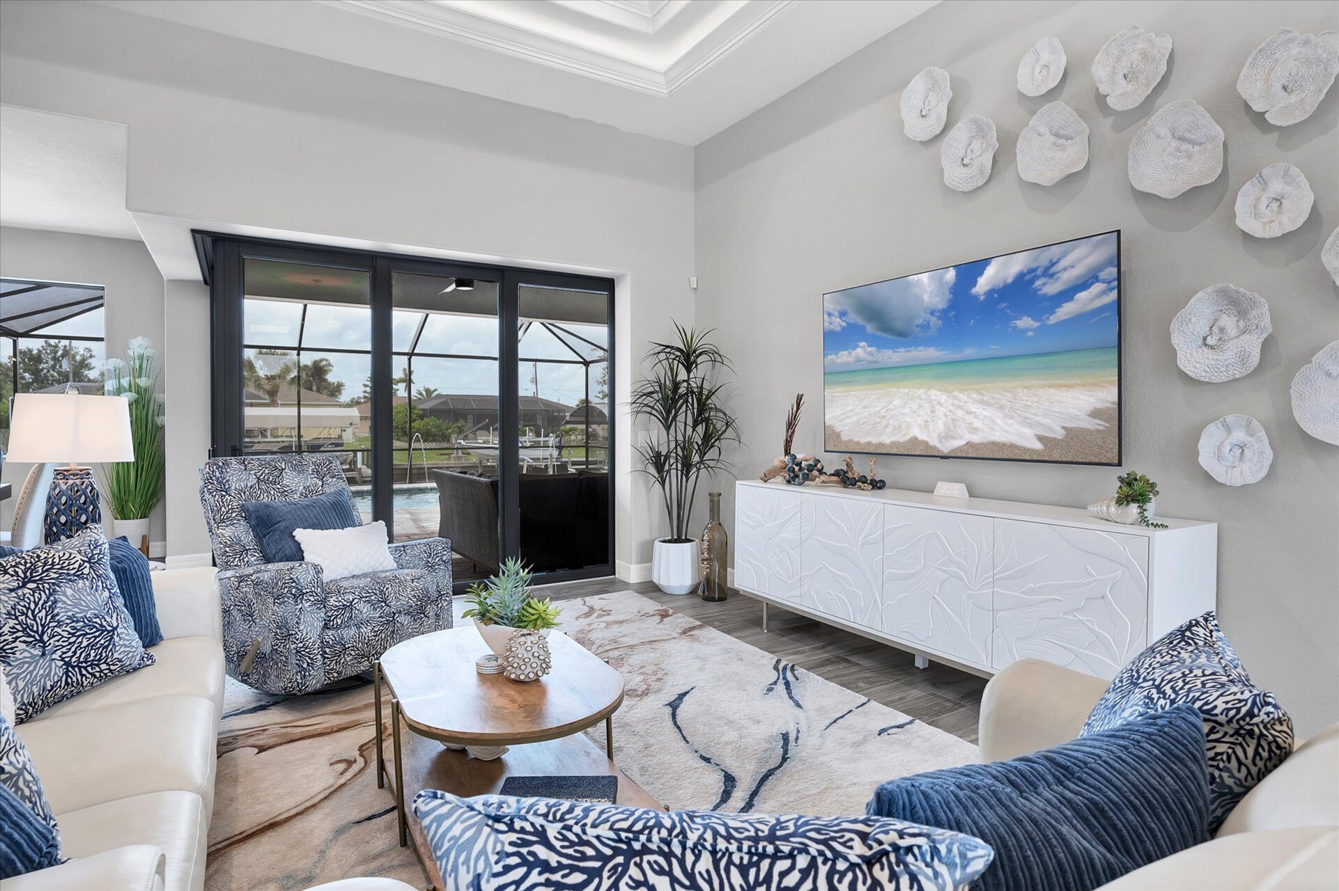 Living room overlooking the sparkling pool and canal beyond. Living room features lots of comfy seating and 75-inch Smart TV