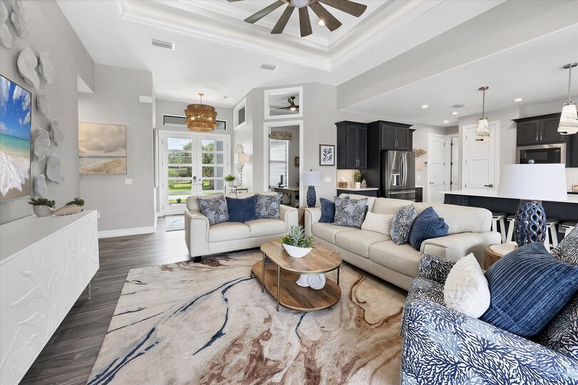 Living room overlooking the sparkling pool and canal beyond. Living room features lots of comfy seating and 75-inch Smart TV